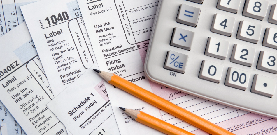 a clutter of tax forms with a calculator and two pencils on top